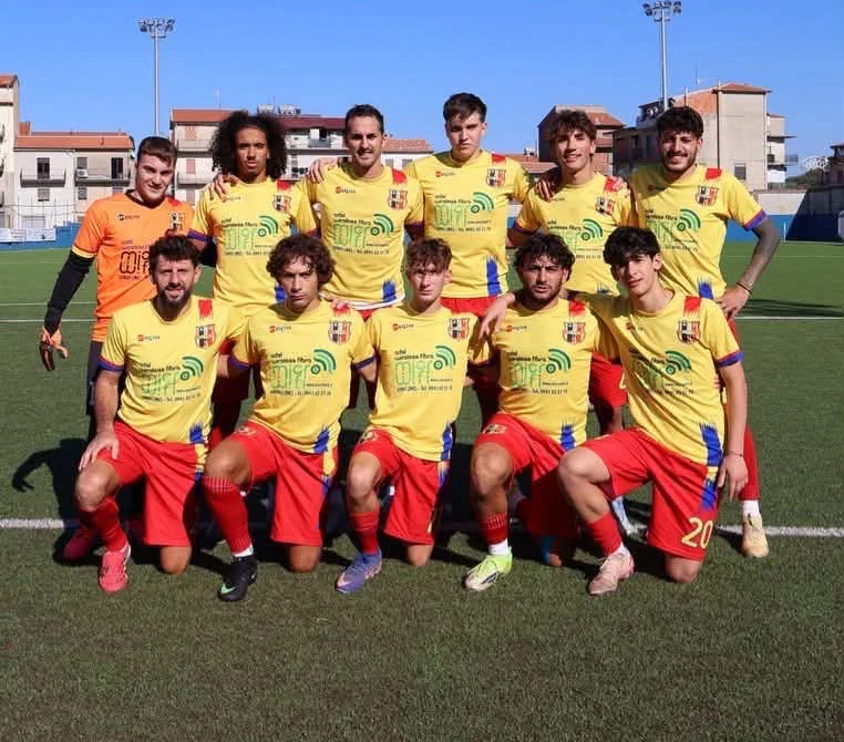 La squadra in posa al campo, in maglia gialla e pantaloncini rossi, con il portiere in arancione